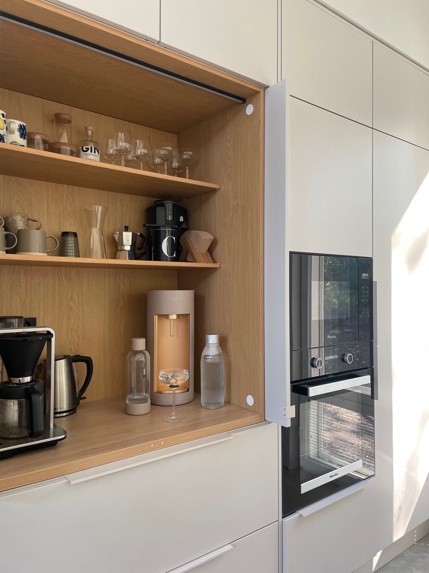 A Glassy sparkling water maker, colour latte in a wood-clad kitchen nook with other drink wear