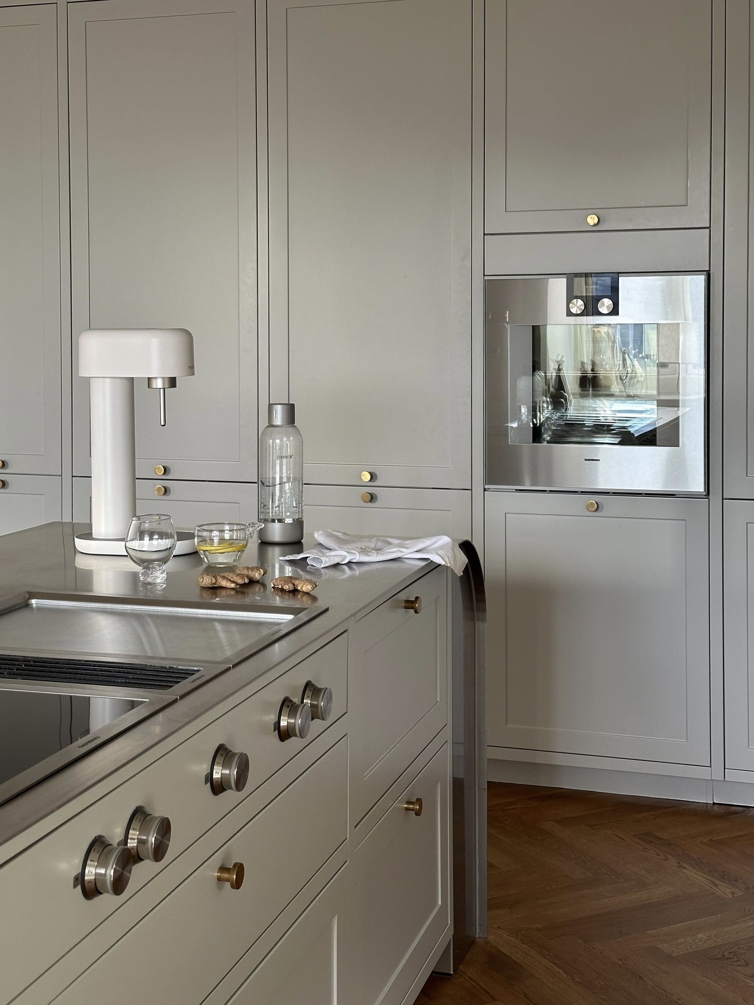 A white and silver Ruby 2 soda maker in a country-style kitchen with brass details and silver appliances