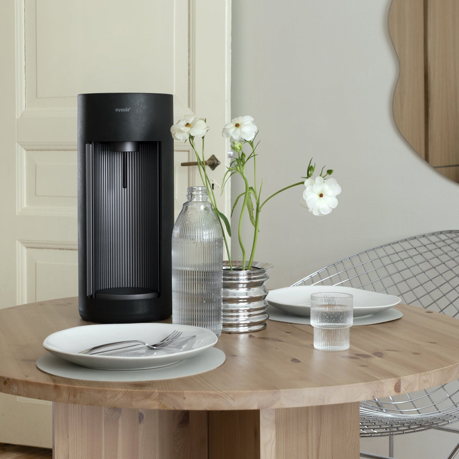 A black Glassy sparkling water maker on a wooden dinner table with minimalistic modern decor