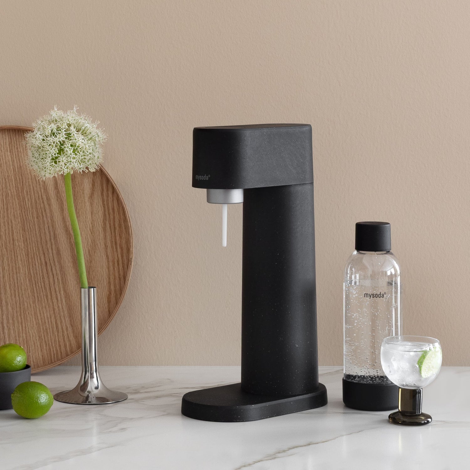 A black woody sparkling water maker and water bottle on an elegant, minimalist kitchen counter