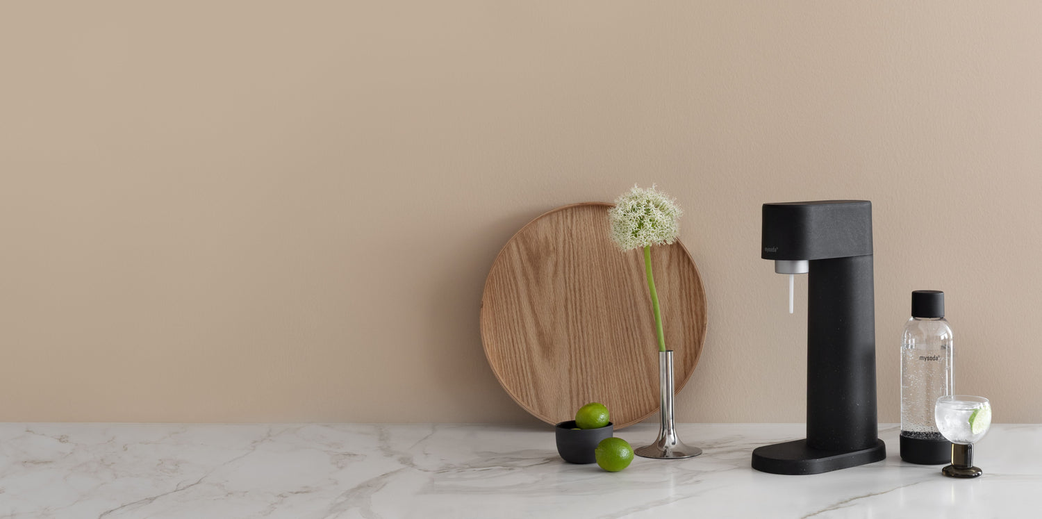 A black woody sparkling water maker and water bottle on a minimally decorated kitchen counter