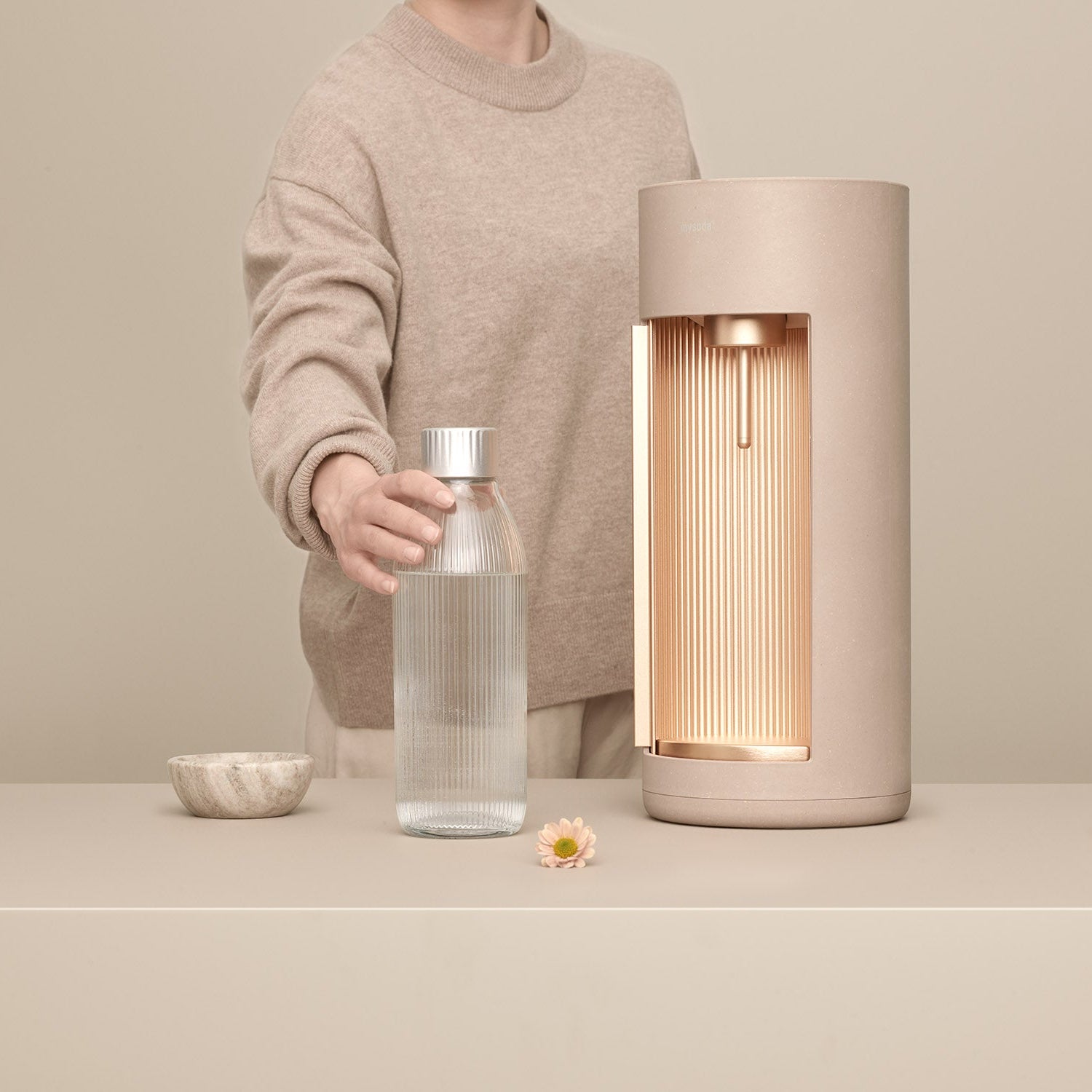 A latte Glassy sparkling water maker and glass bottle in front of latte background