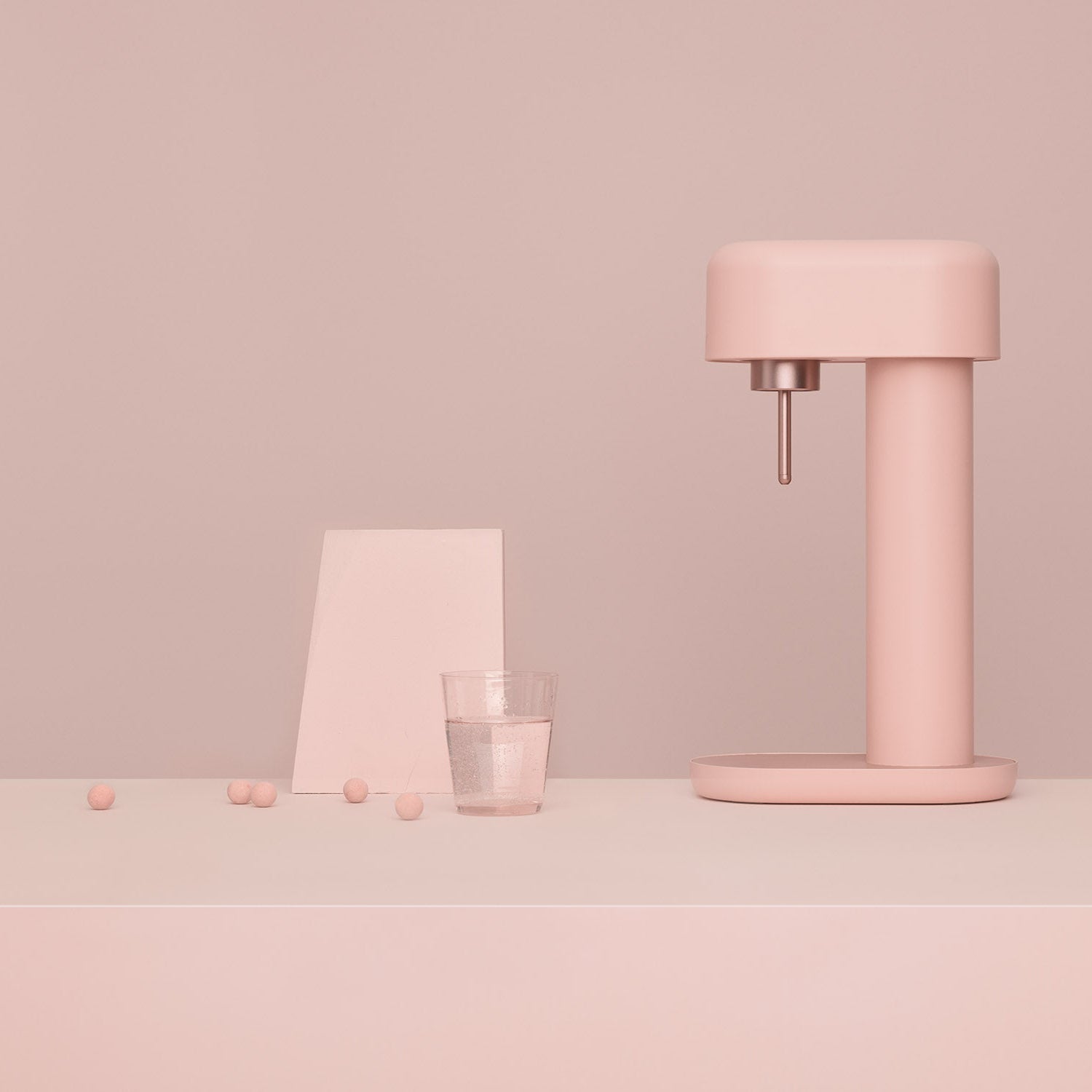 A pink Ruby 2 and a glass of water in front of tone-to-tone pink background#väri_pink