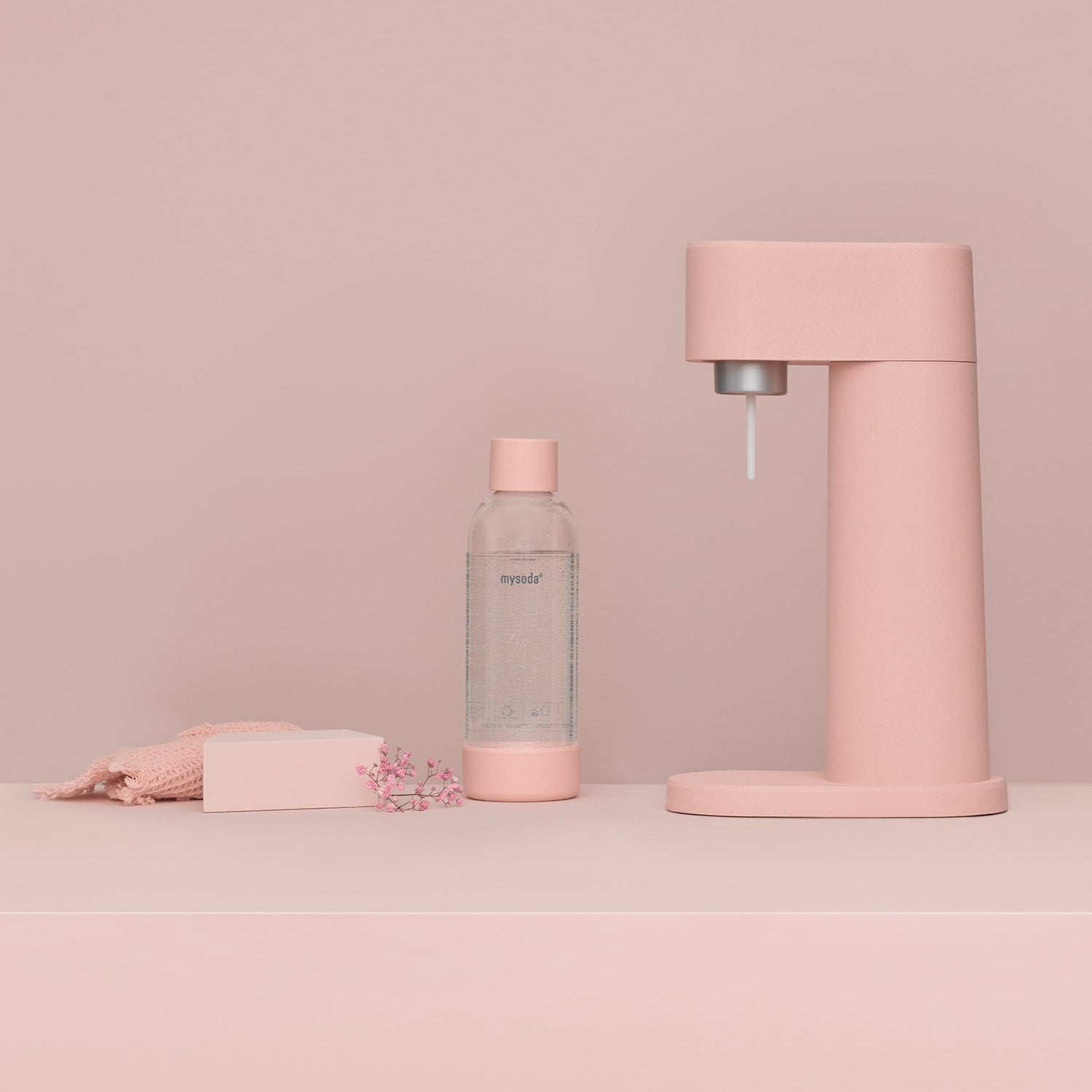 A pink Woody sparkling water maker and matching water bottle in an all-pink setting