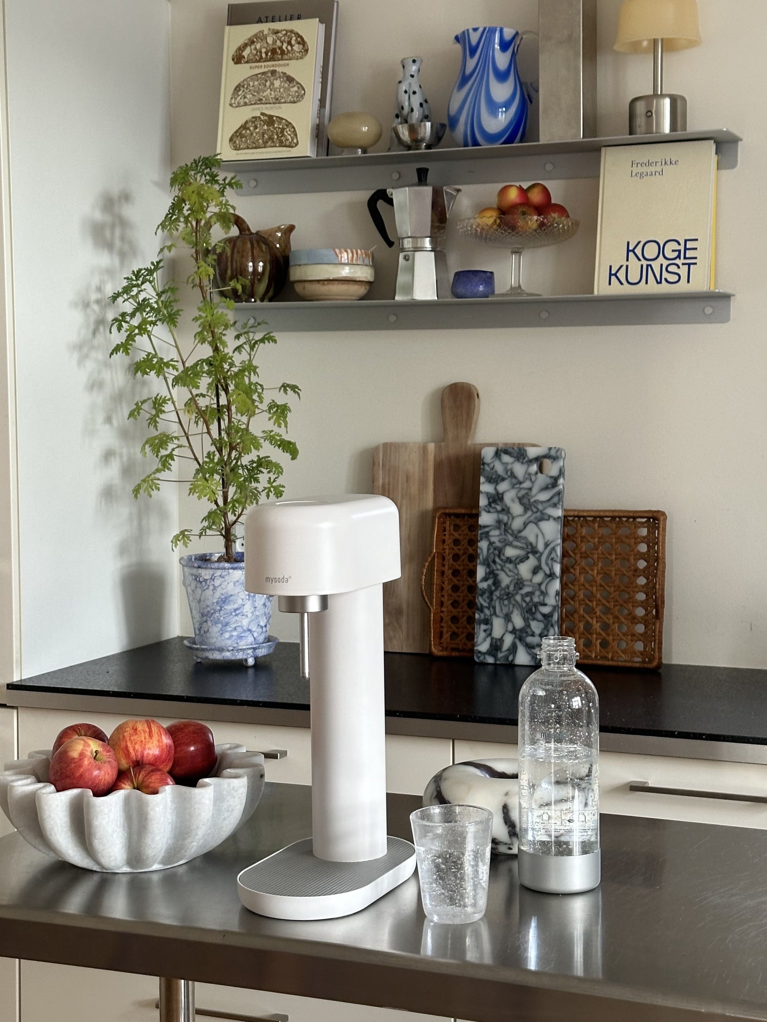 A white and silver Ruby 2 sparkling water maker in a kitchen with vibrant colour accents from blue porcelain and red fruit