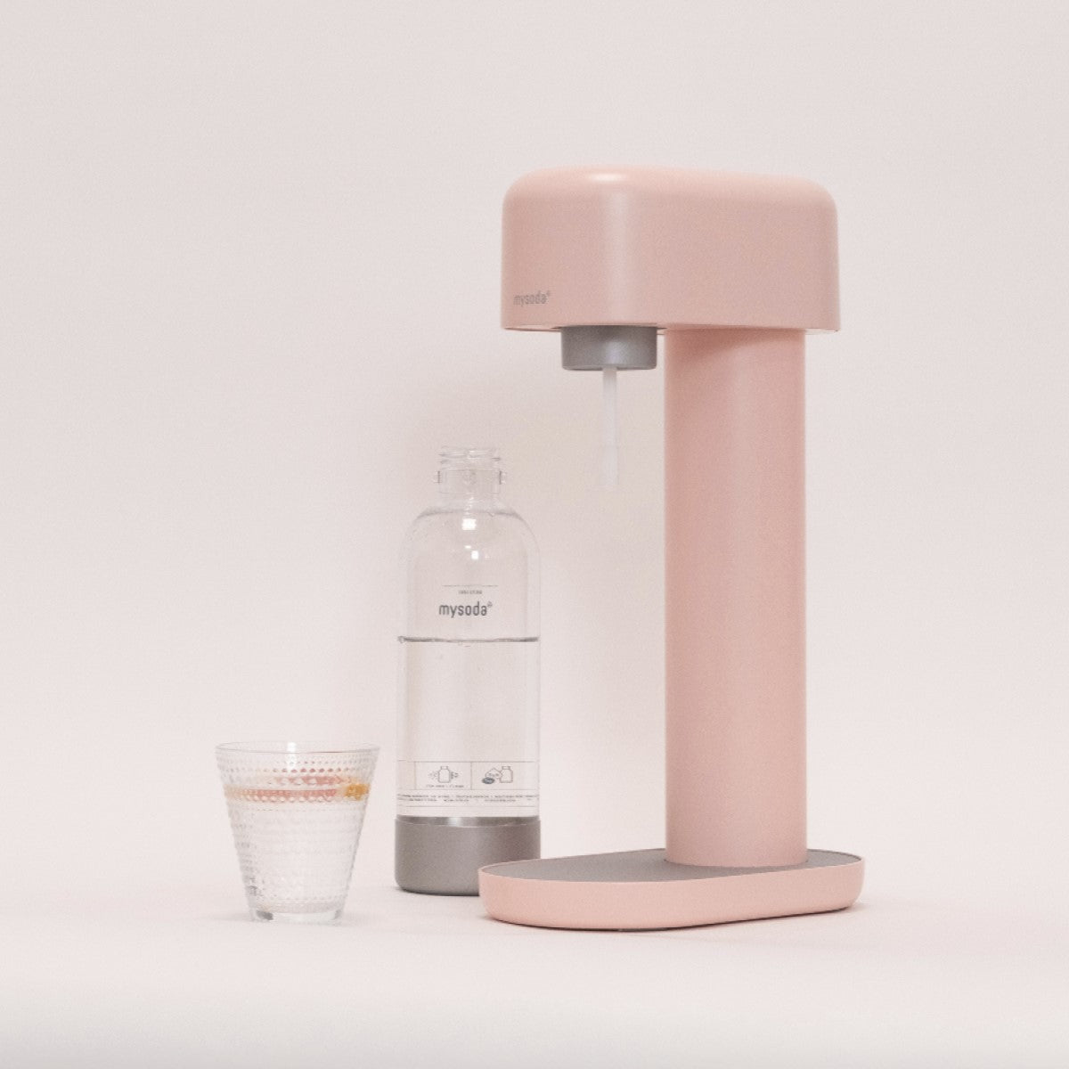 A light pink Ruby sparkling water maker, a bottle and a glass of water