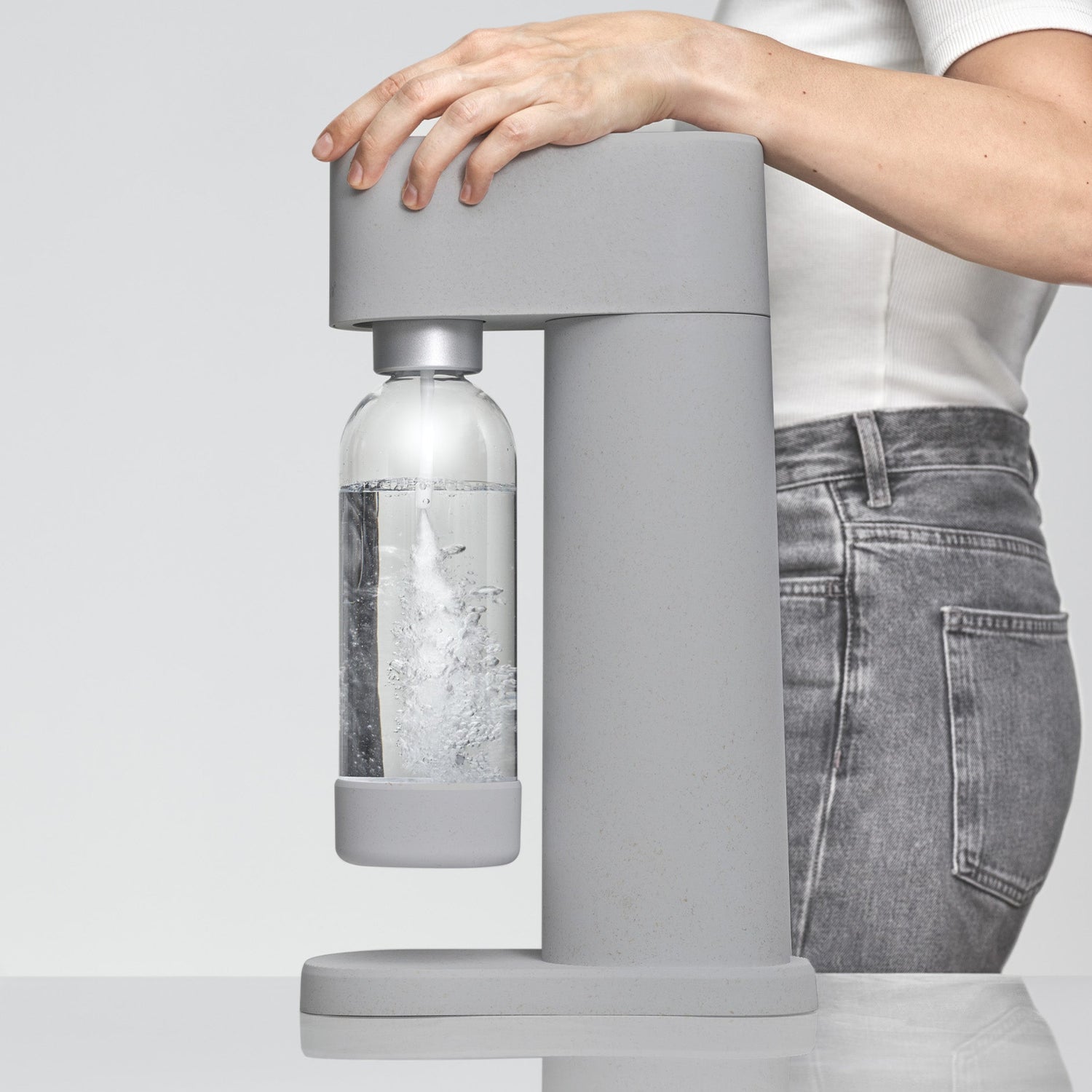 A woman resting her arm on a gray Woody sparkling water maker