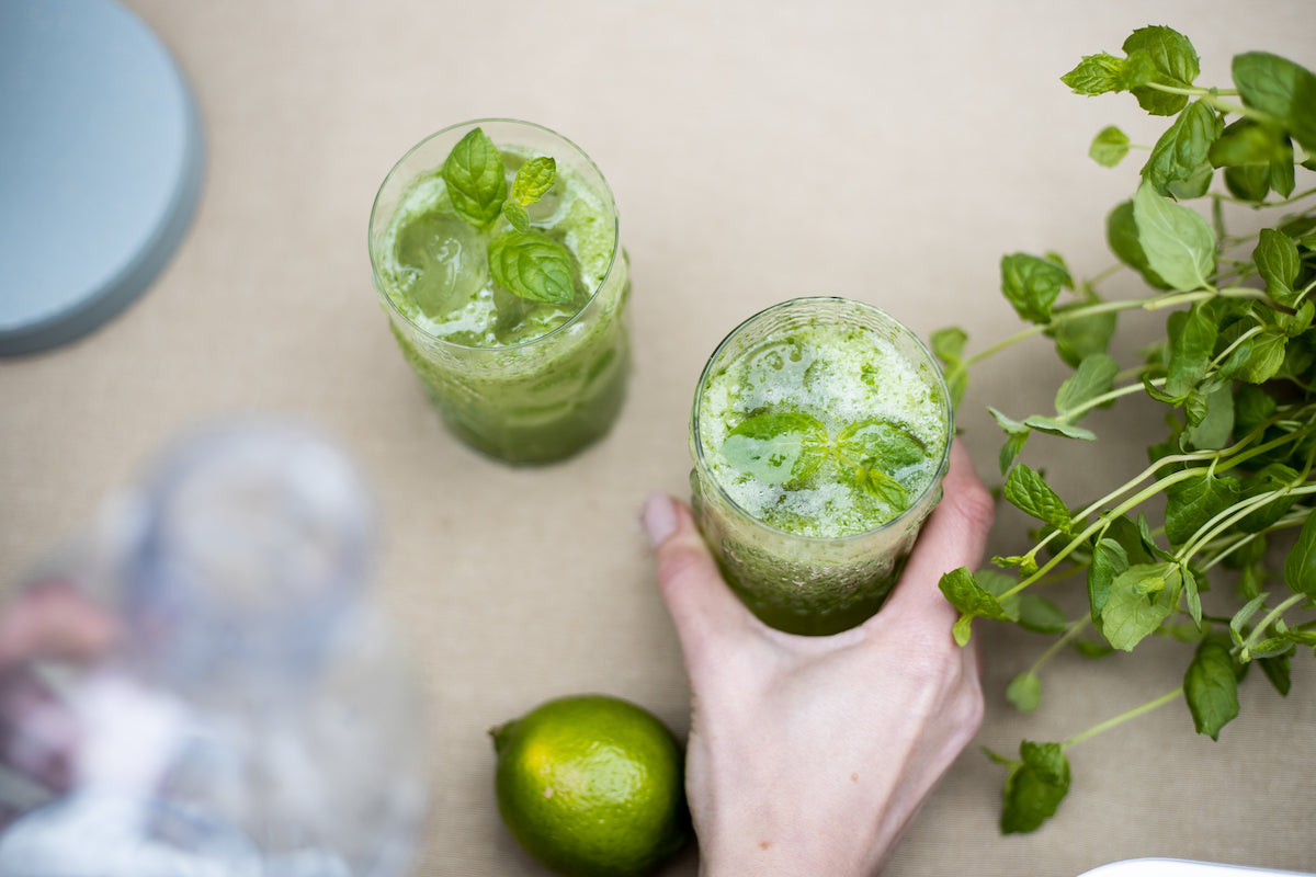 Two glasses of bright green cucumber lime mocktail seen from the top town