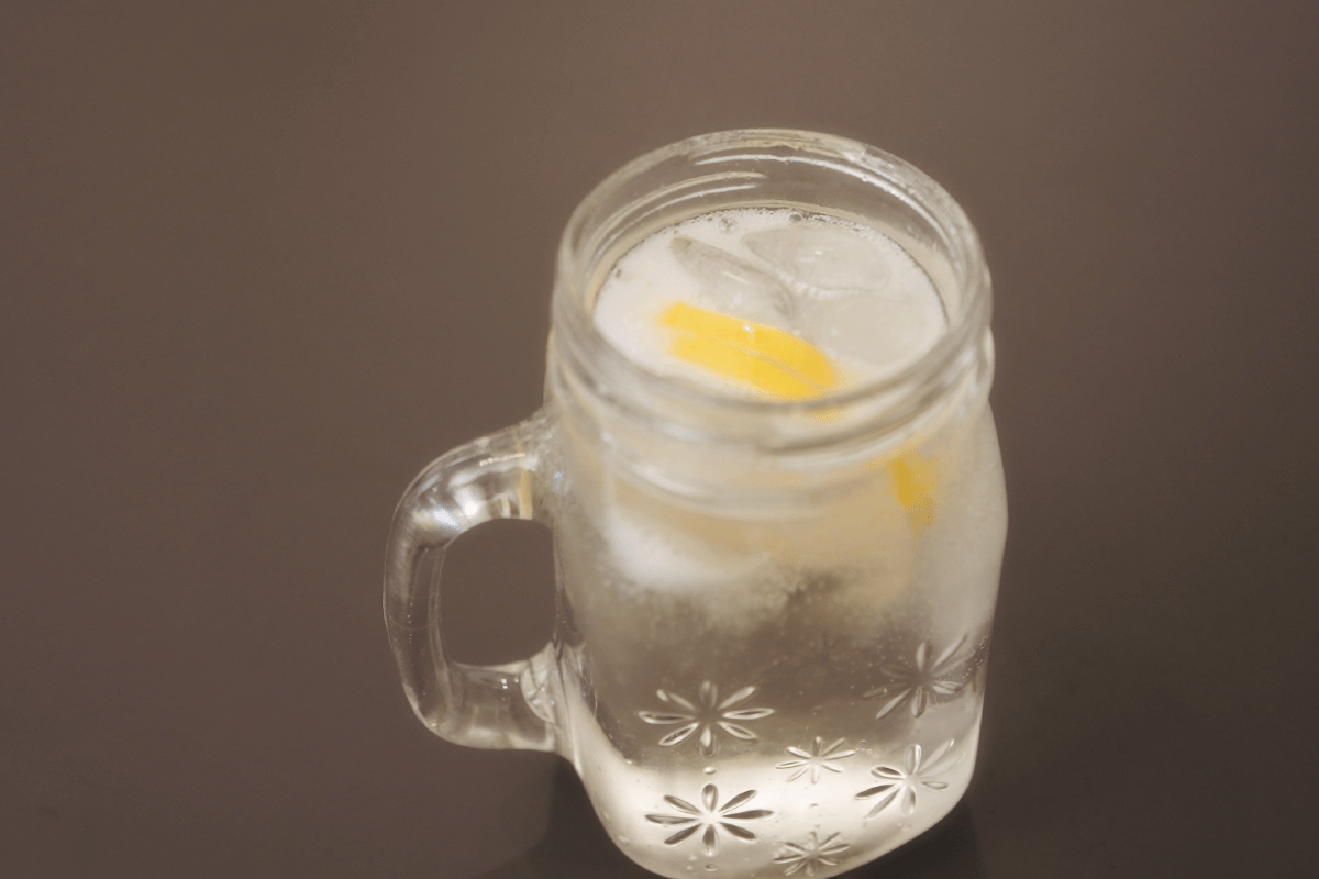 A glass of ice cold elderflower mocktail on a black surface
