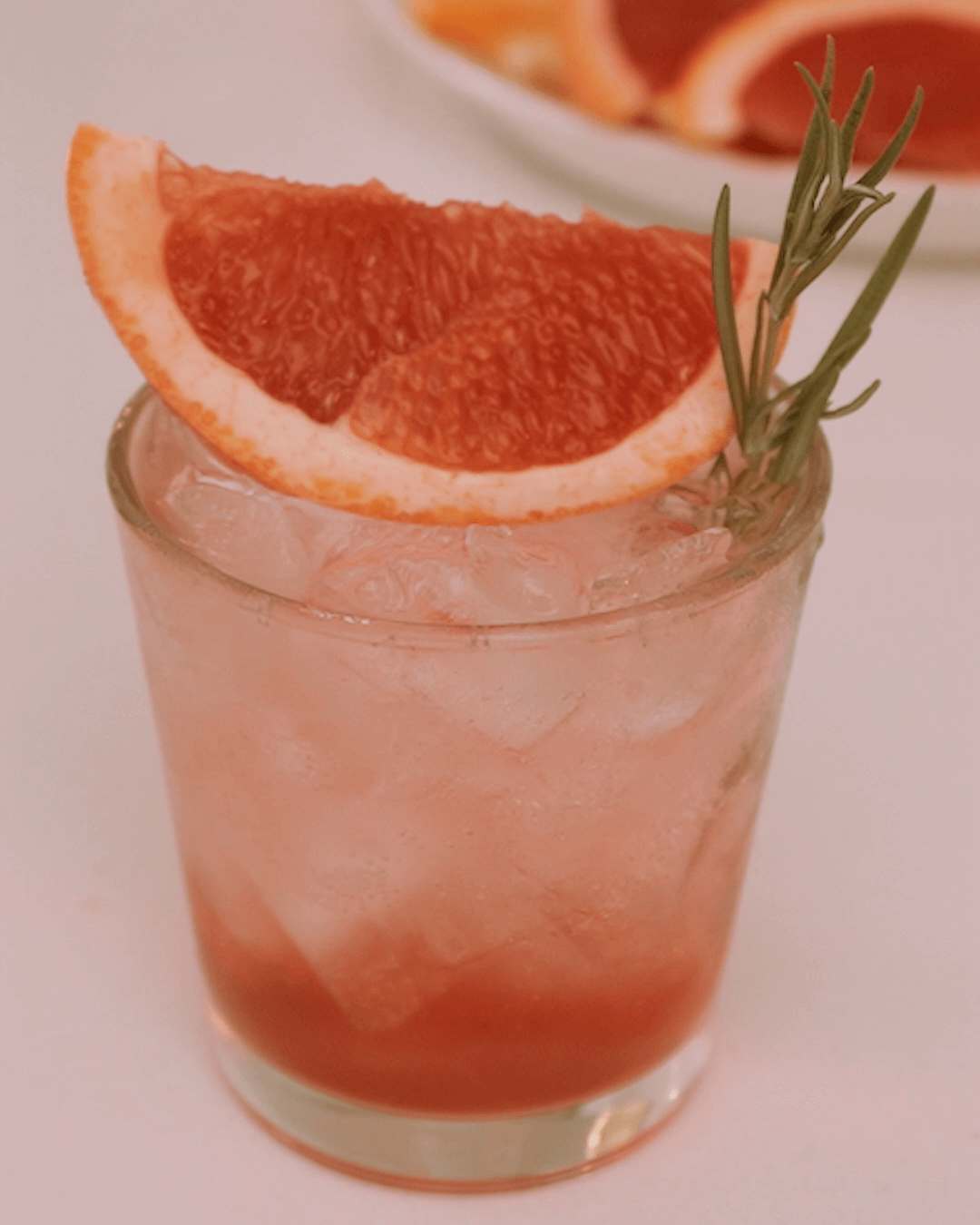 A Glass of iced grapefruit mocktail decorated with a grapefruit piece balancing on top