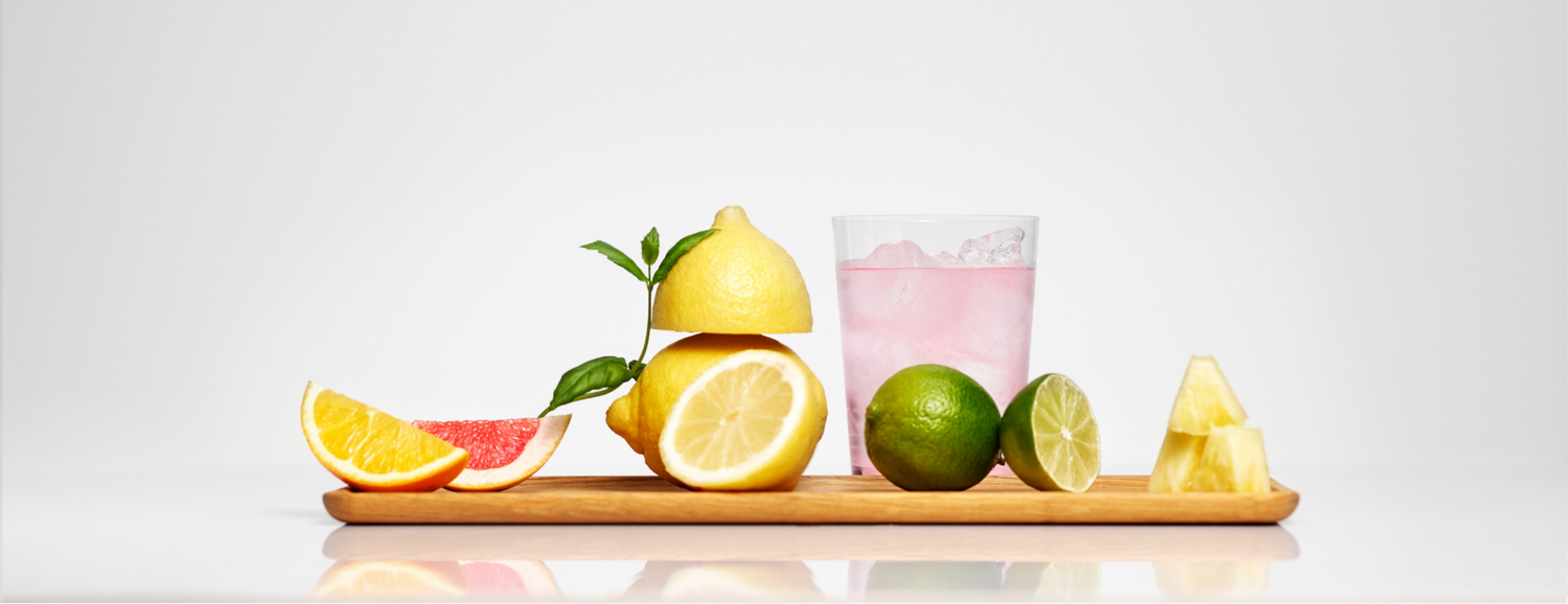 A board with pieces of citrus fruit and a glass of light.-pink fizzy drink