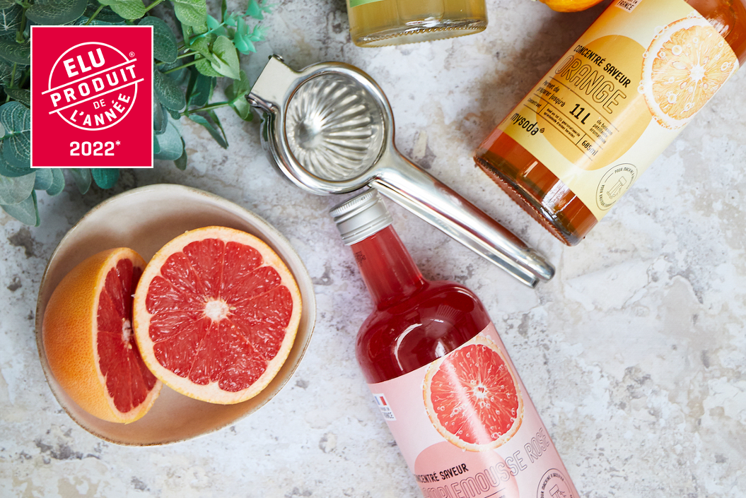bottles of Mysoda drink mixes of the French assortment, grapefruit and some utensils spread over a countertop. The product of the year logo in the top left corner