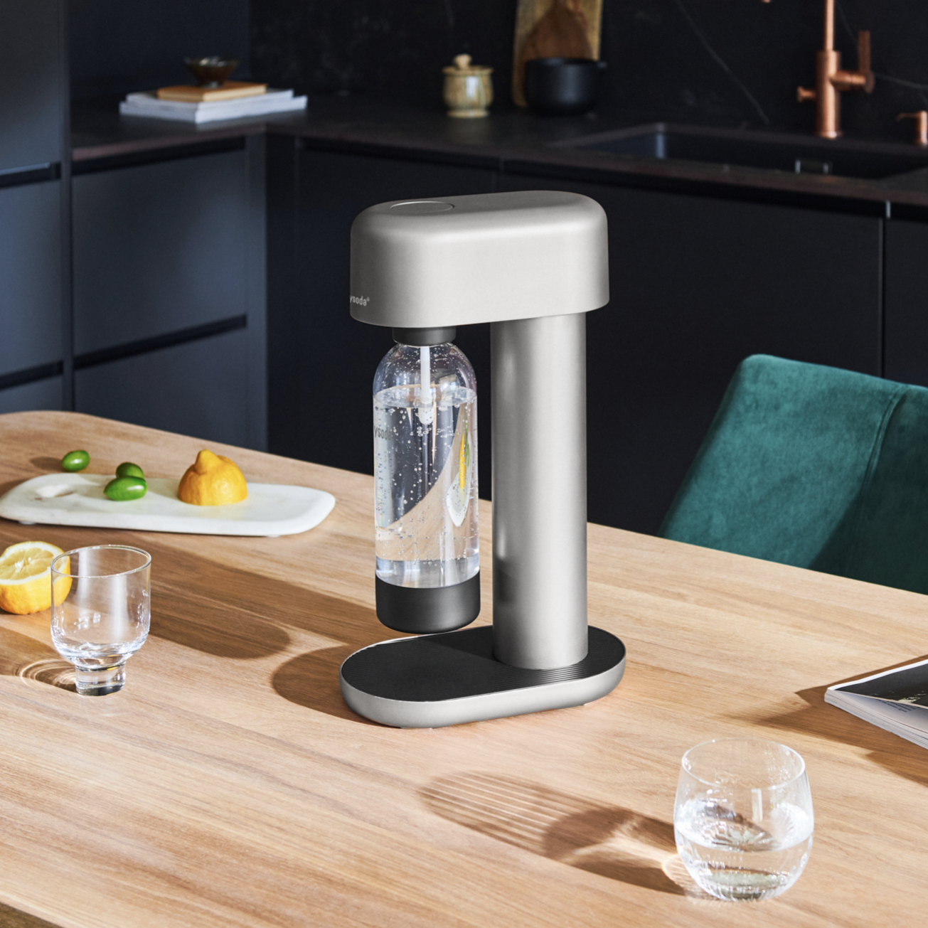 A silver Ruby soda machine on a wooden kitchen table in a black kitchen