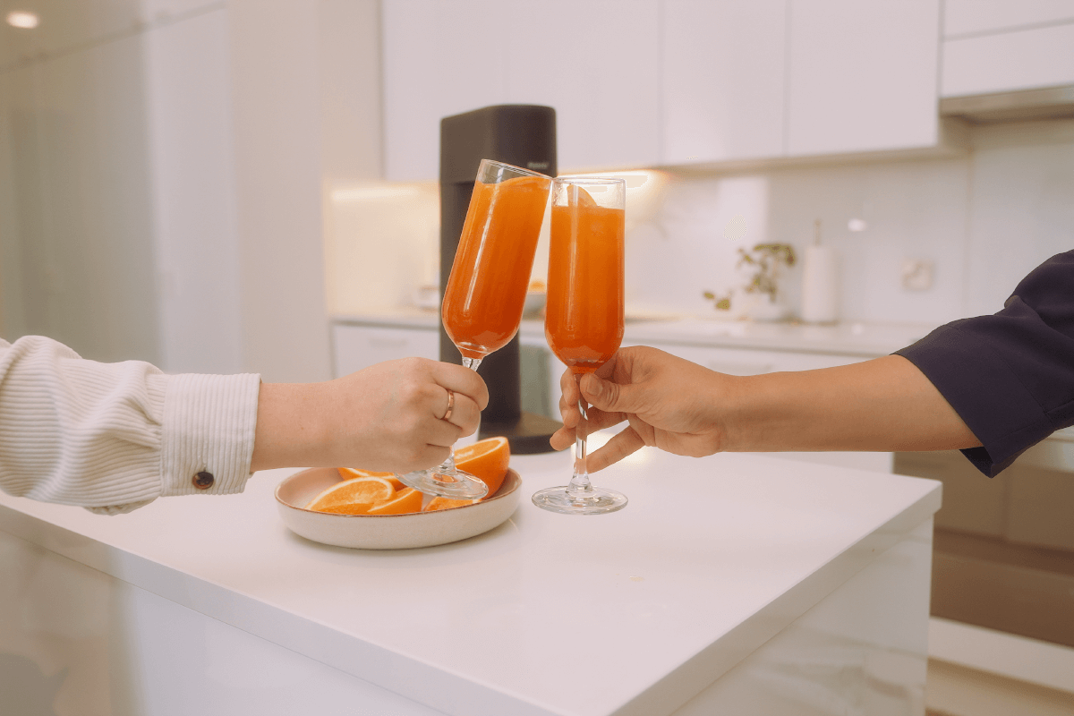 Two people toasting with glasses of orange mocktail