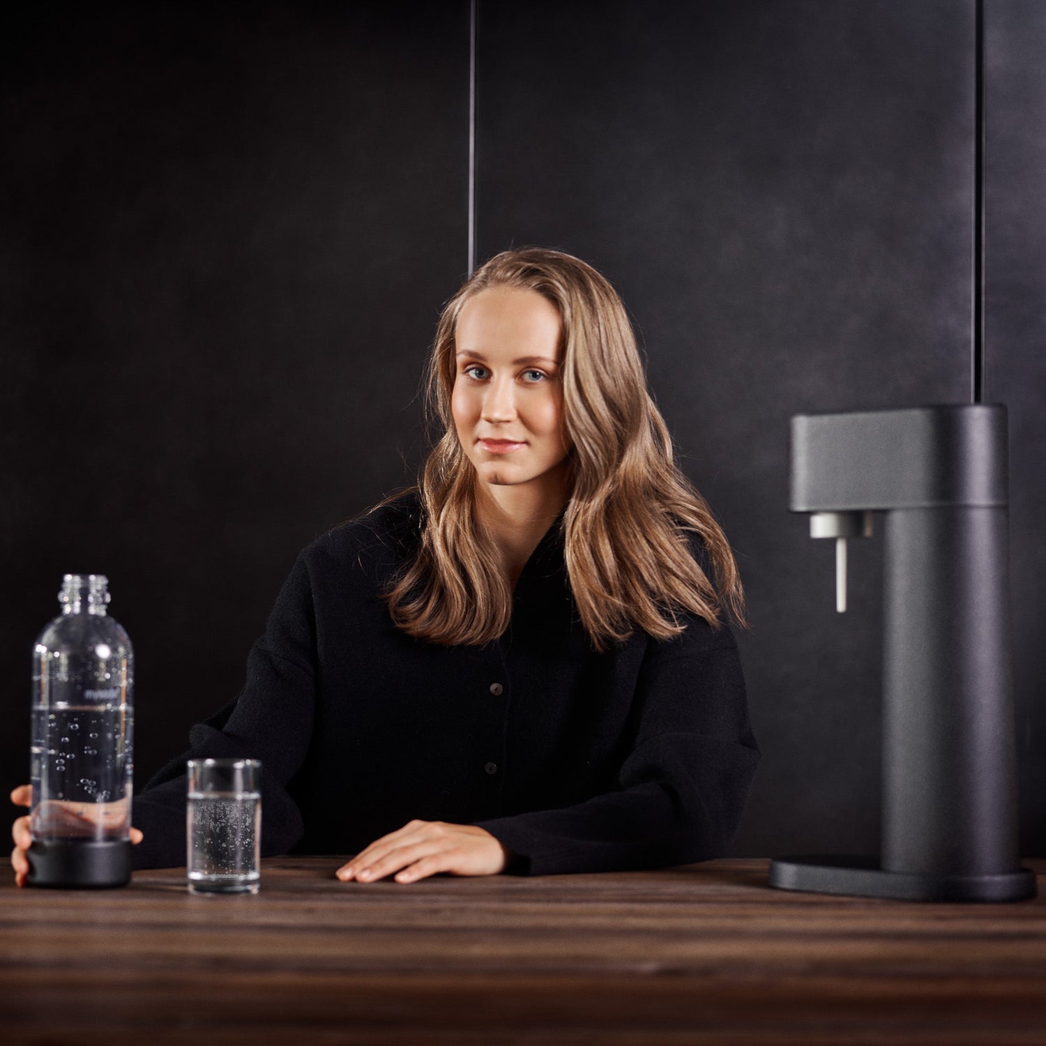 Hurdler Viivi Lehikoinen enjoying a drink of sparkling water with Mysoda Woody. A black Woody sparkling water maker and respective PET water bottle are visible.