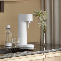 A white Woody sparkling water maker  and water bottle on a kitchen counter