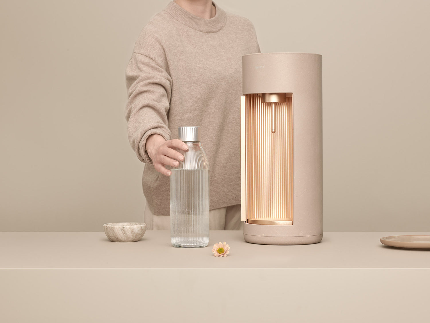 A latte Glassy sparkling water maker and glass bottle in front of latte background