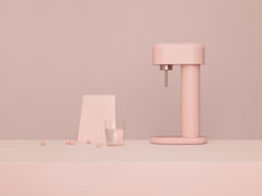 A pink Ruby 2 and a glass of water in front of tone-to-tone pink background#väri_pink