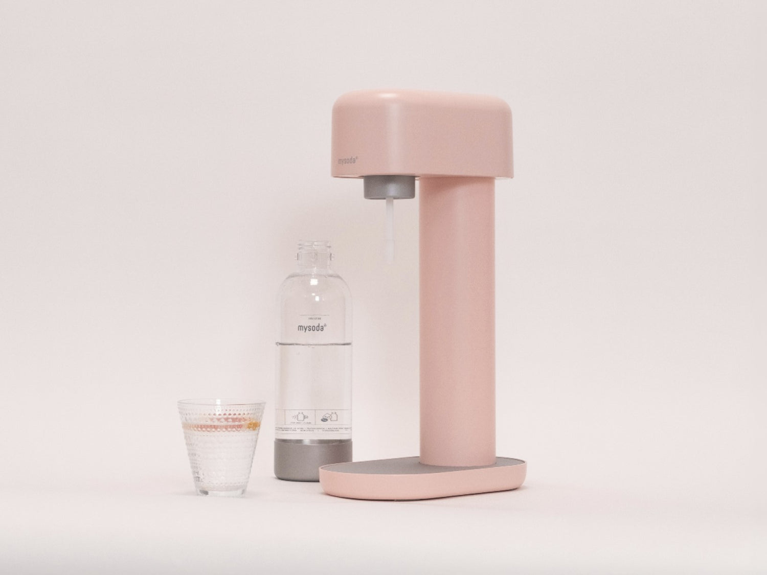 A light pink Ruby sparkling water maker, a bottle and a glass of water