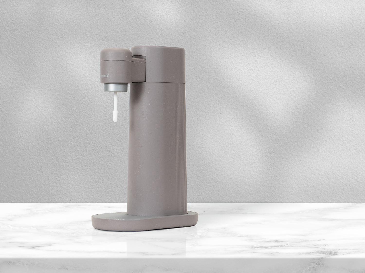 A dove grayish Mysoda Toby sparkling water maker on a marble counter in rays of sunlight