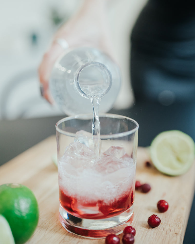 Sparkling water is poured over a glass of ice cubes and Mysoda drink mix Cranberry