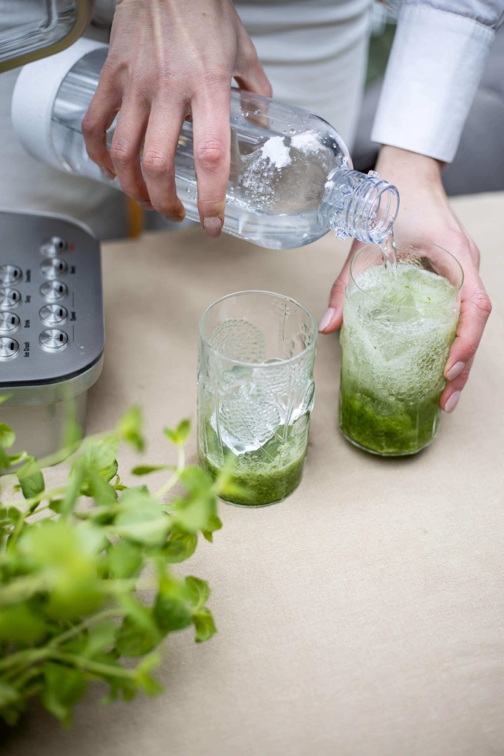 Water being poured onto the prepared mixture for a refreshing cucumber lime mocktail