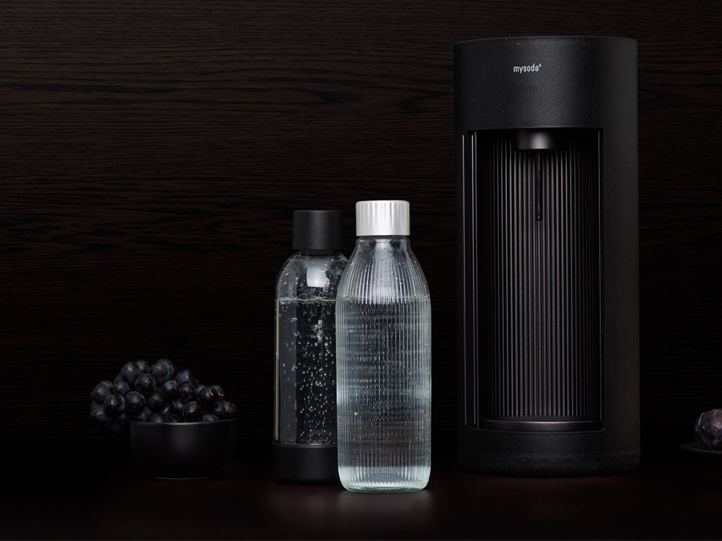 A black glassy with matching glass and PET water bottles in a dark environment