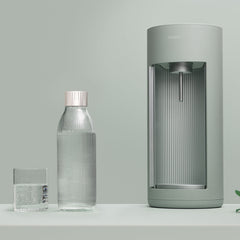 A pigeon-coloured Glassy sparkling water maker and glass bottle on tone-to-tone background