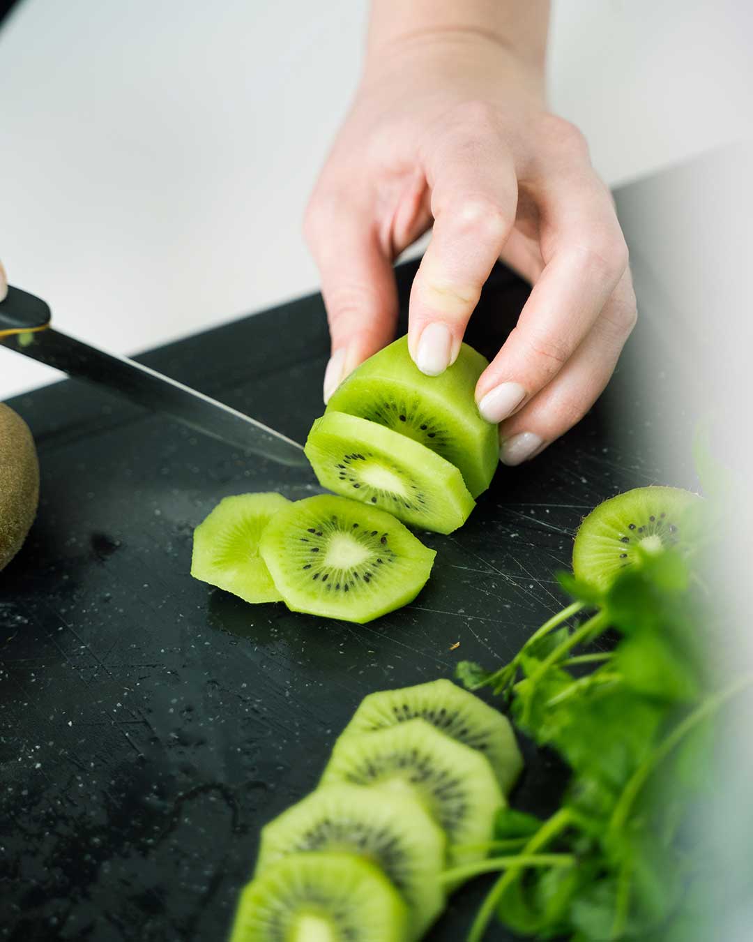 A fresh kiwi being cutt into slices