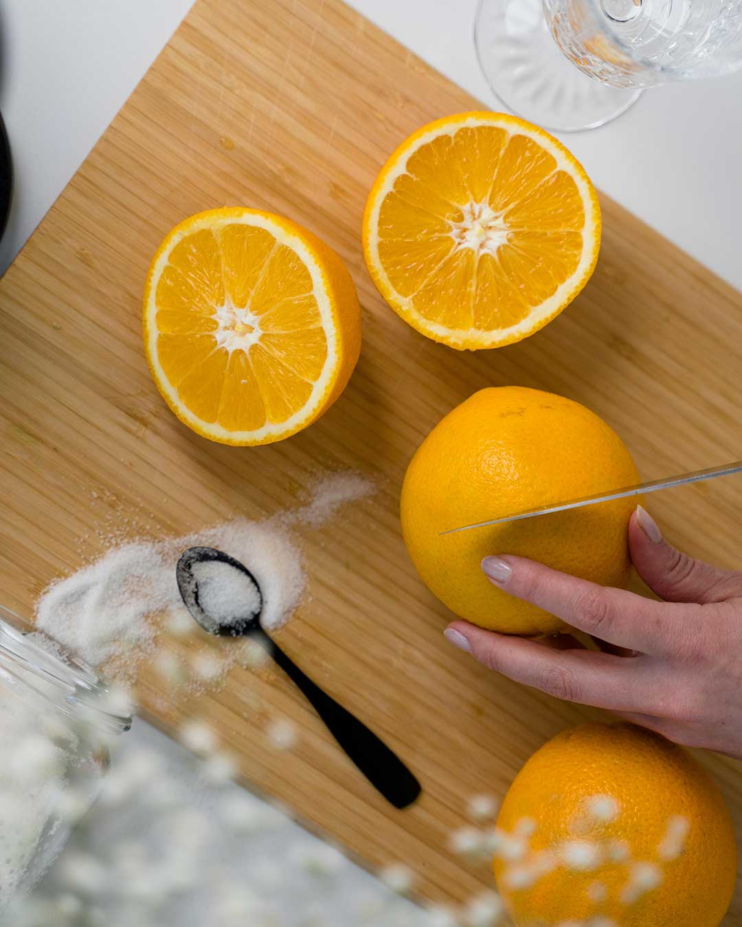 Oranges being cut in half on wooden cutting board