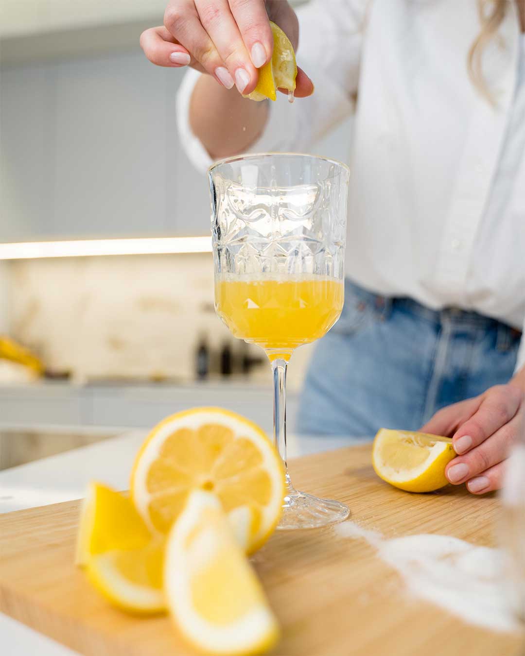 Fresh lemon juice being squeezed into a tall glass