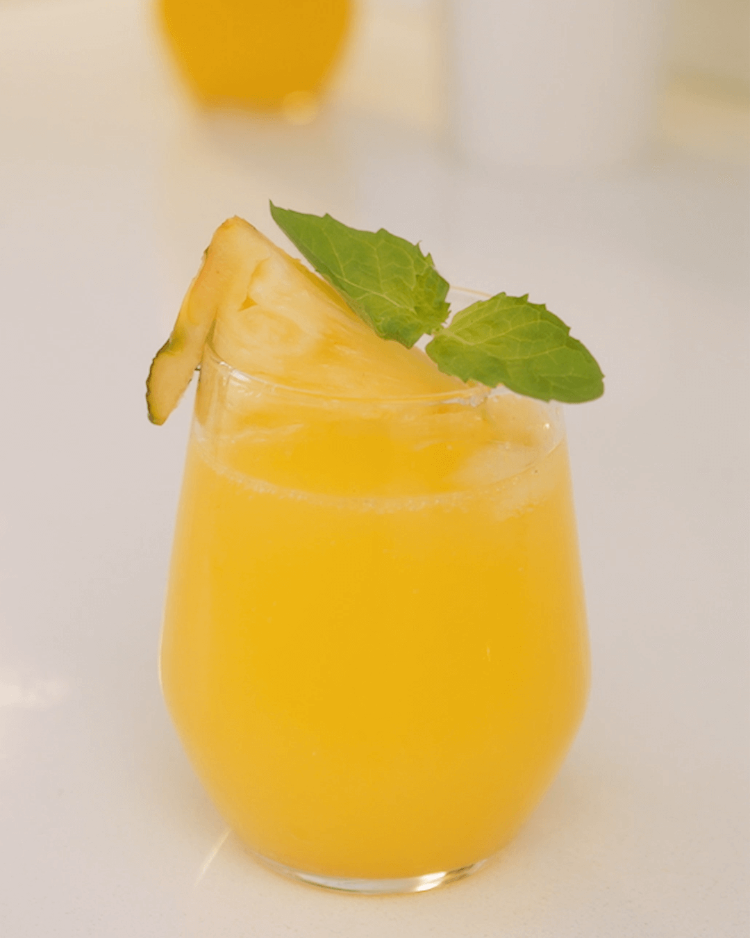 Closeup of a glass of pineapple mocktail decorated with fresh mint