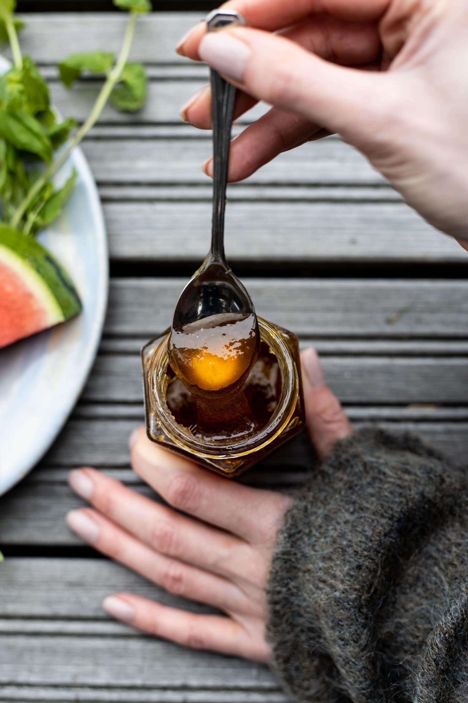 Closeup of female hands taking a spoonfull of honey from a glass