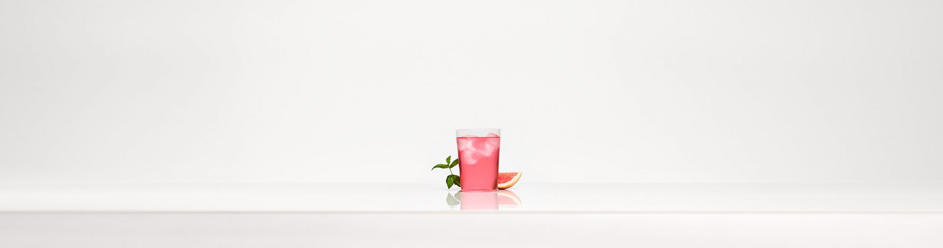 Un verre de boisson gazeuse rose sur un fond blanc.