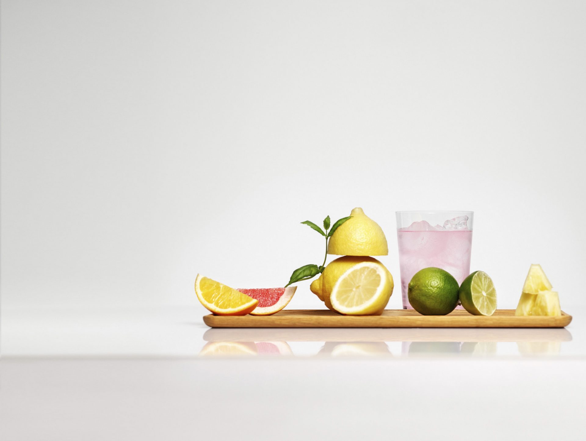 Et glas lyserød sodavand og frugt på et bræt