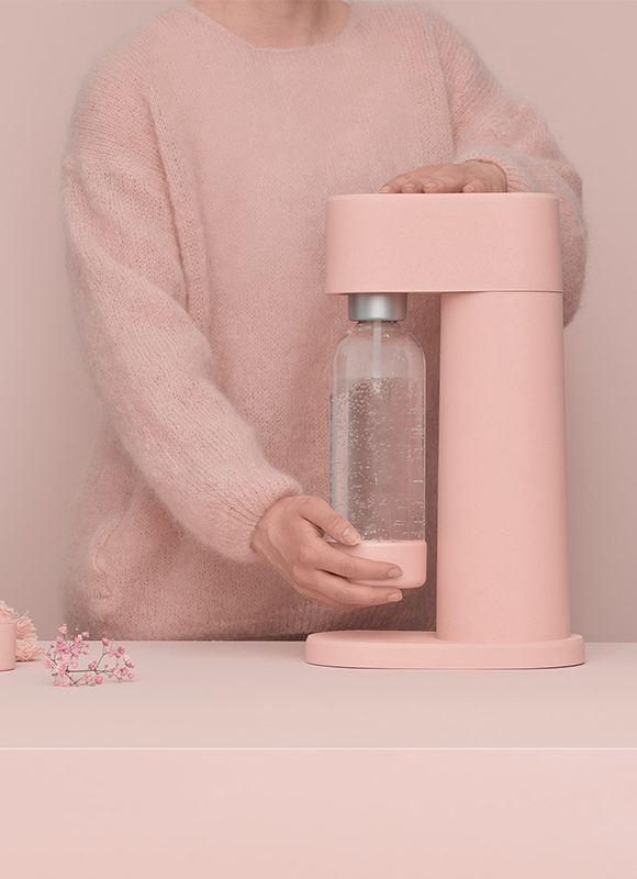 En rosa Mysoda Woody sprudlende vannmaskin brukes av en kvinne i et rosa miljø