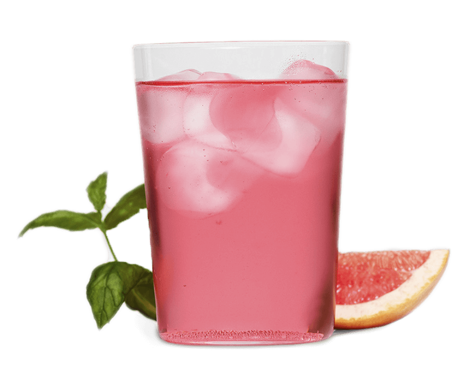 ett glas rosa kolsyrad dryck framför en vit bakgrund