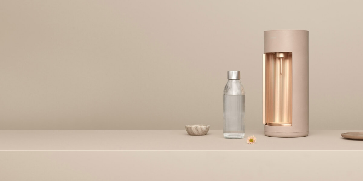 A latte coloured Mysoda Glassy sparkling water maker and glass bottle in front of tone-to-tone backgound